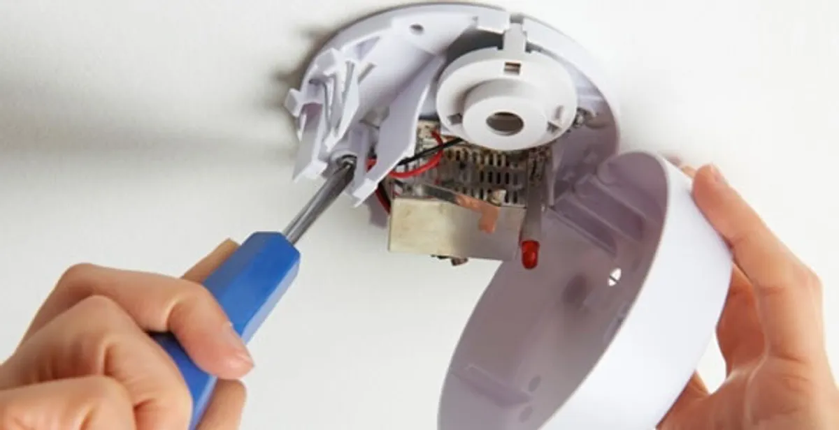 Certified technician wiring smoke detector during installation in Littleton, CO